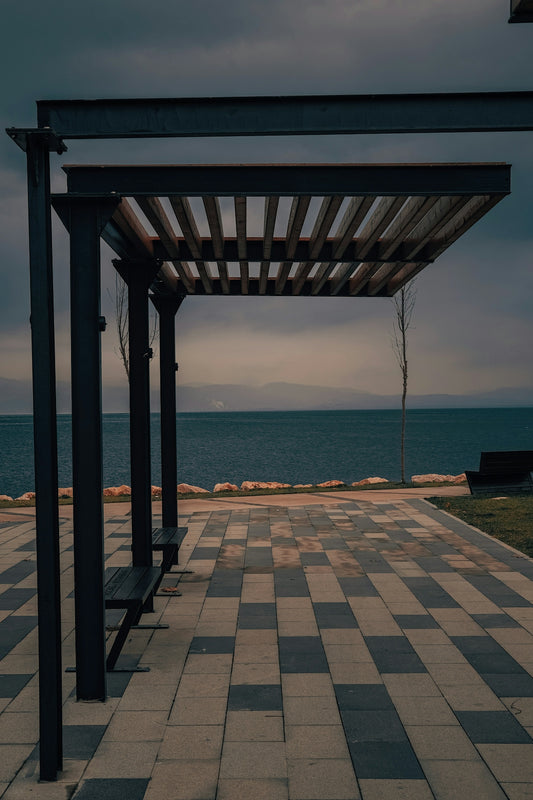 a bench sitting on top of a tiled walkway next to the ocean