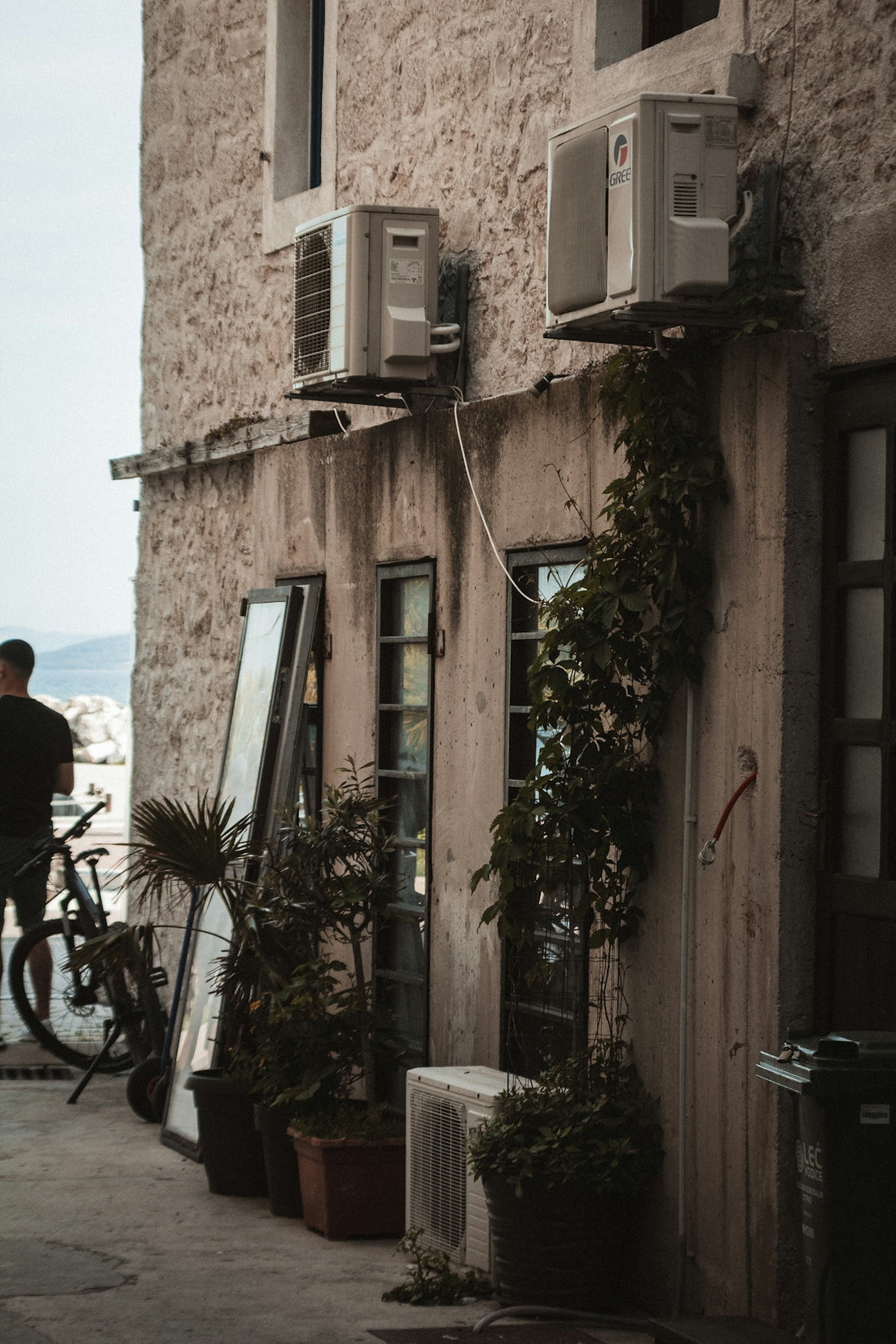 a man standing next to a building with a bike parked next to it