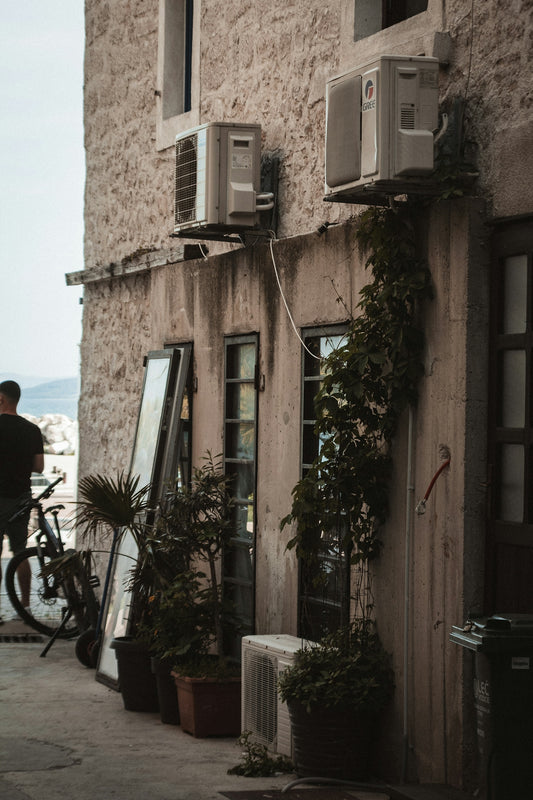 a man standing next to a building with a bike parked next to it