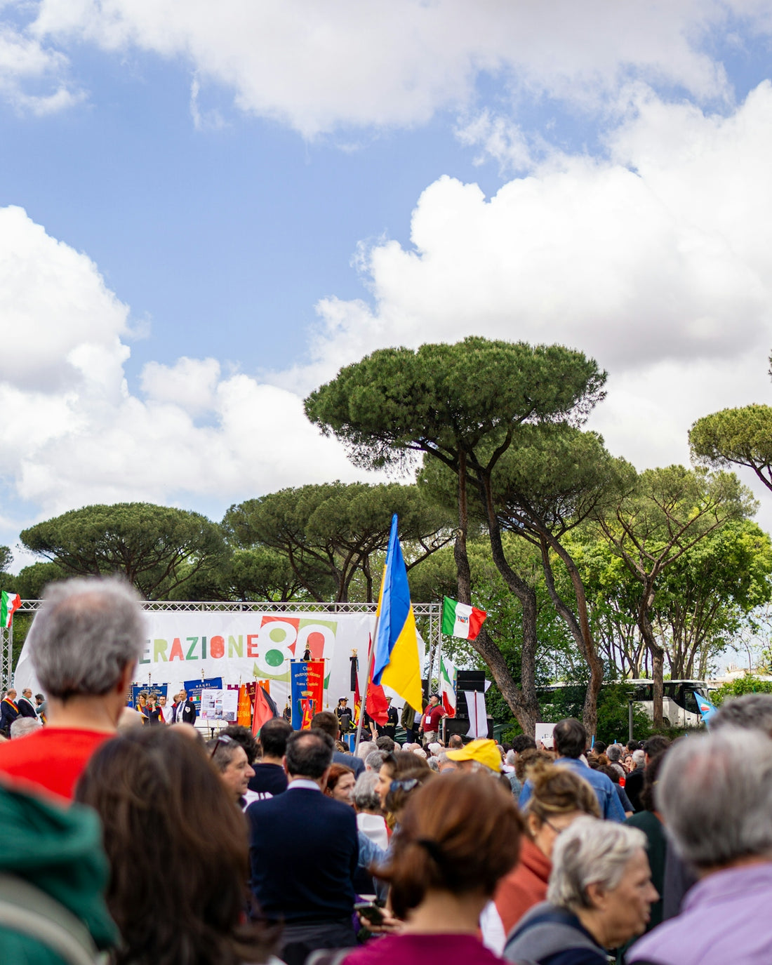 People gather for an outdoor event with flags.