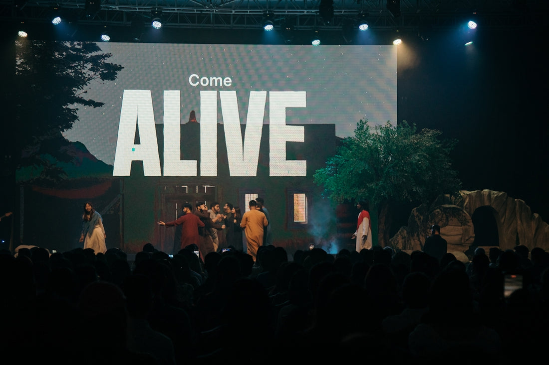 People on stage with come alive text on screen